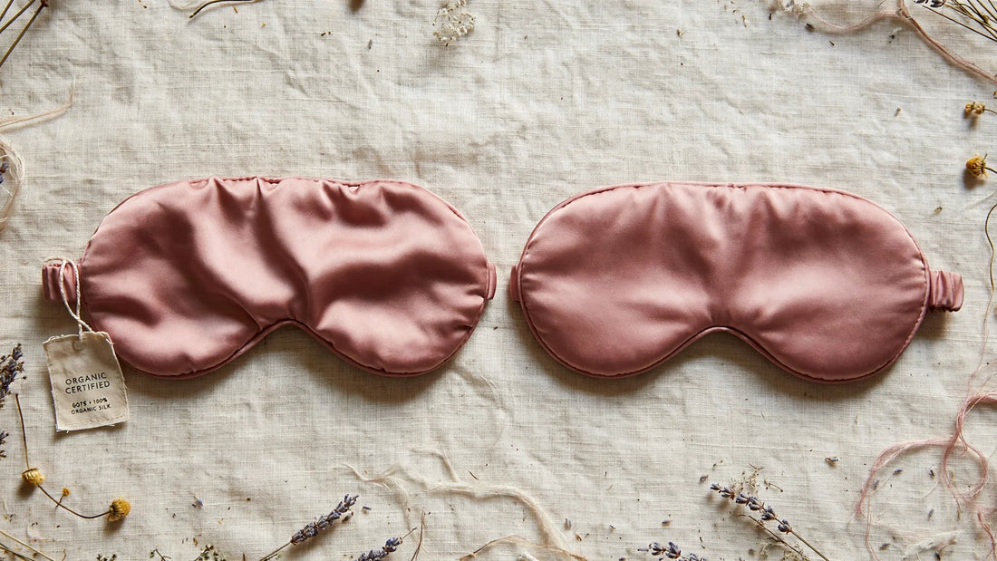 Deux masques de sommeil en soie rose poudré côte à côte, l'un avec une étiquette bio certifiée