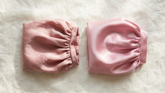 Comparaison côte à côte d'un bonnet en soie mat et d'un bonnet en satin brillant, posés sur du lin ivoire