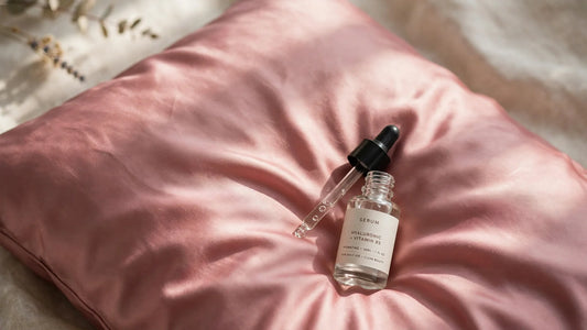 Taie d'oreiller en soie rose poudré avec un flacon de sérum de soin de la peau