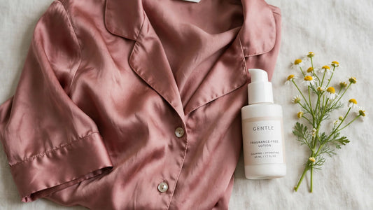 Pyjama en soie rose poudré posé a plat a cote d une lotion douce sans parfum et d un brin de camomille